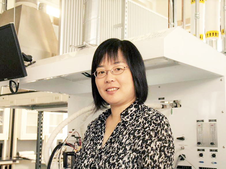 Maggie Chen wearing print blouse in front of lab